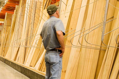 man looking at planks of wood in a builders merchants